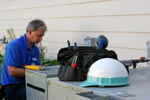 tech performing maintenance on ac unit