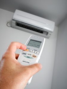person-adjusting-heat-pump-thermostat-with-a-remote