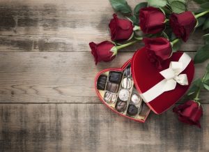 box-of-chocolates-and-bouquet-of-roses-on-a-wooden-tabletop